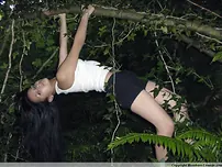 Pretty Indian chick suspends from a tree limb in a tank top and cut-offs