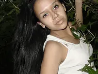 Pretty Indian chick suspends from a tree limb in a tank top and cut-offs