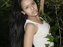 Pretty Indian chick suspends from a tree limb in a tank top and cut-offs